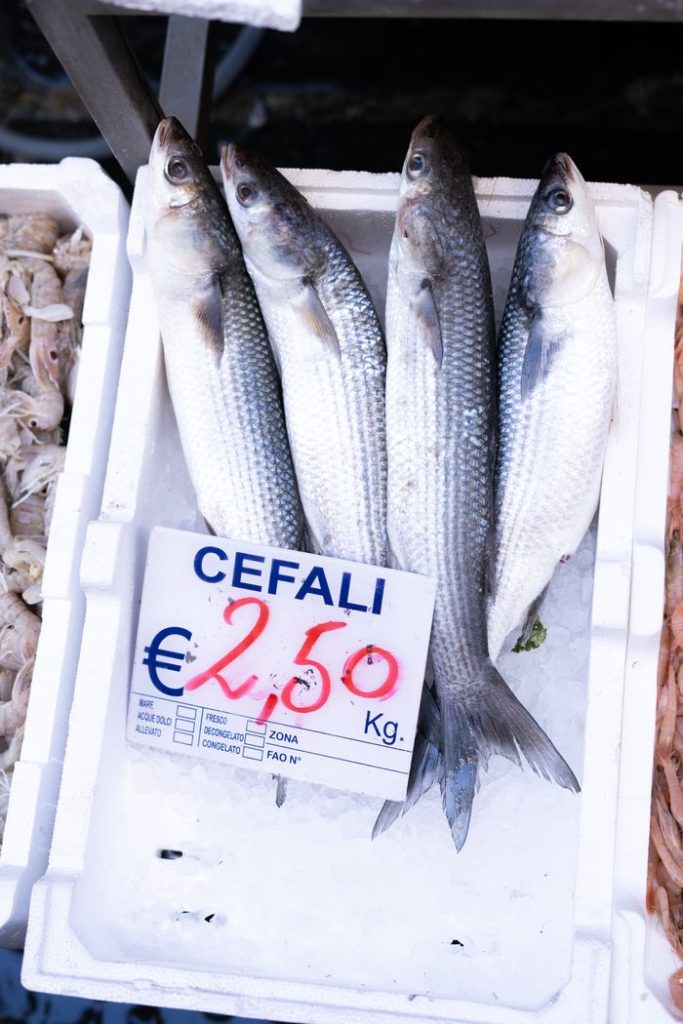 Fresh mullet fish on ice with price tag at a seafood market in Naples, Italy.